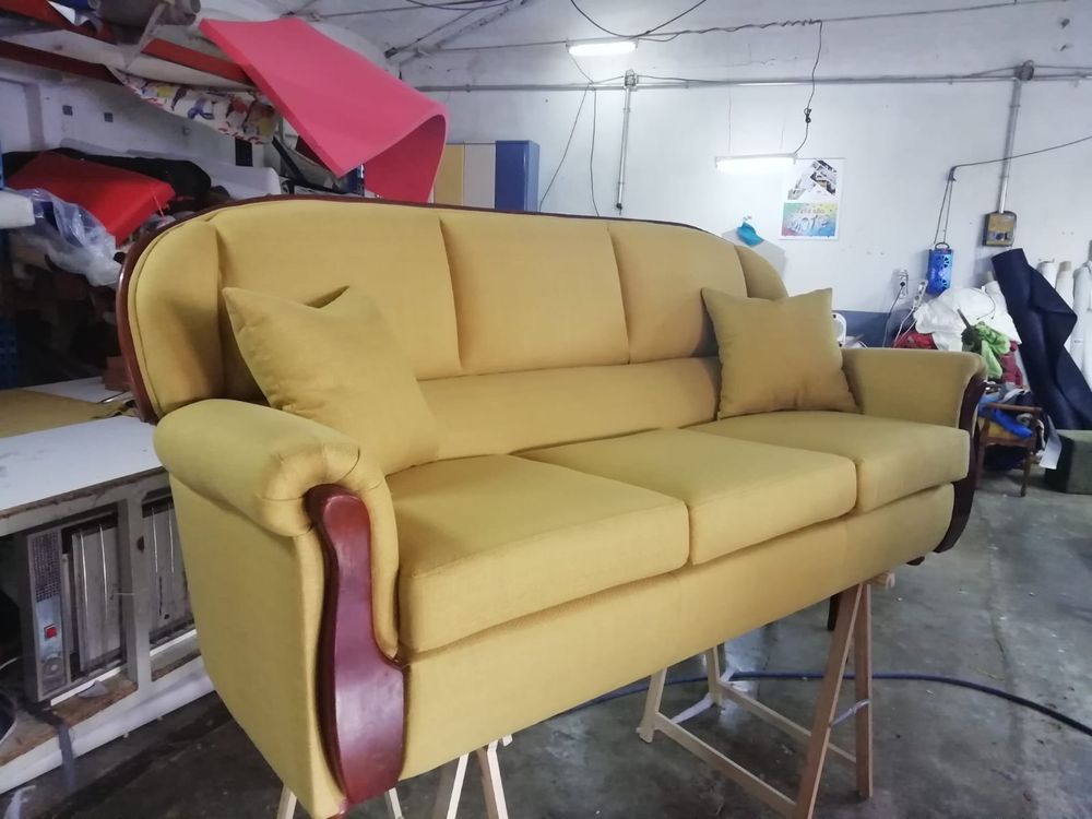 Sofá clásico tapizado en amarillo mostaza con brazos de madera